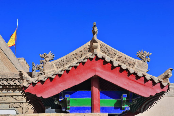 Xieshan style roof on wooden beams of pavilion in the inner city-flag on turret at the NW corner of the brick and rammed soil wall of the Jiayu Guan Pass fortress. Jiayuguan city-Gansu province-China. - Φωτογραφία, εικόνα