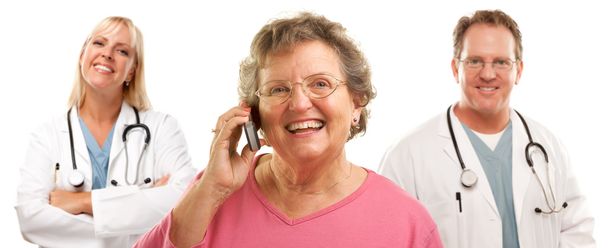 Heureuse femme âgée utilisant le téléphone cellulaire et les médecins derrière
 - Photo, image
