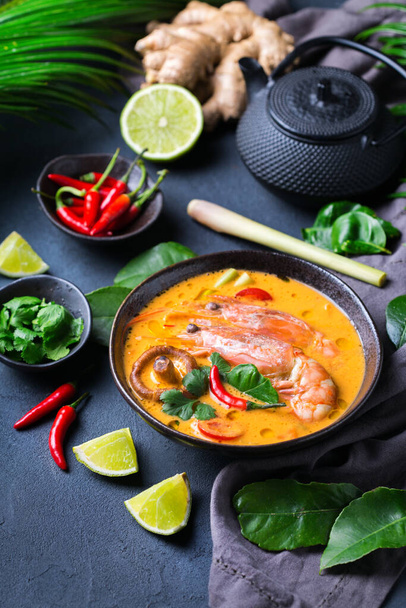 Eten en drinken, traditionele Thaise keuken. Pittige tom yam kung, tom yum zure soep met garnalen, garnalen, kokosmelk, citroengras en chili peper in een kom op een tafel - Foto, afbeelding