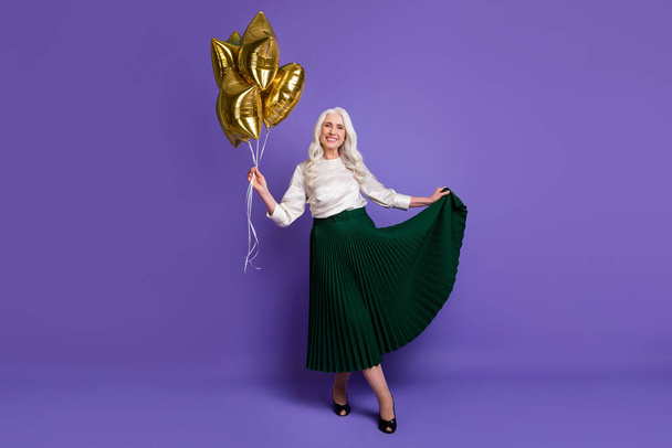 Full length photo of charming satisfied lovely old woman enjoy family celebration hold star shaped baloons touch long skirt isolated over purple color background - Photo, image