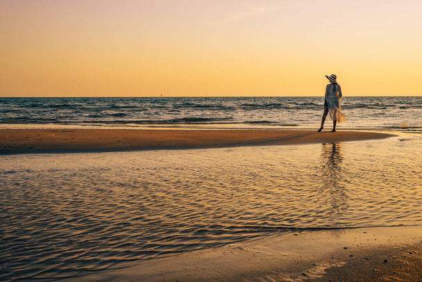 Egy fiatal nő áll a parton napnyugtakor, nyári vakáción.. - Fotó, kép