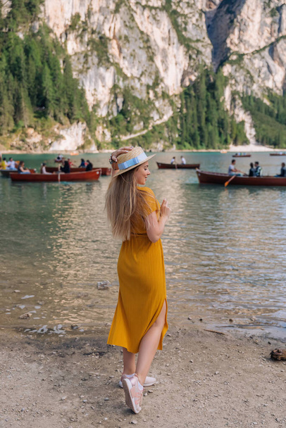 дівчинка в сукні і човні на березі гірського озера з дерев'яними човнами. Dolomites, Italy. - Фото, зображення