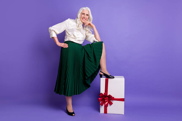 Full length body size view of her she nice attractive fashionable cheerful cheery grey-haired woman putting leg on giftbox isolated on bright vivid shine vibrant lilac violet purple color background - Φωτογραφία, εικόνα