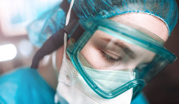 молодая женщина хирург врач в форме и очки в операционной во время пандемии
. - Фото, изображение