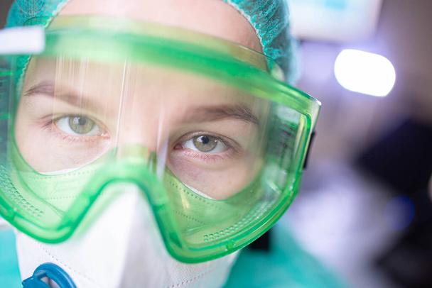 young woman surgeon doctor in uniform and goggles in the operating room during a pandemic. - Photo, Image