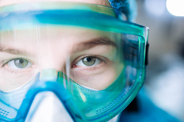 young woman surgeon doctor in uniform and goggles in the operating room during a pandemic. - Foto, afbeelding