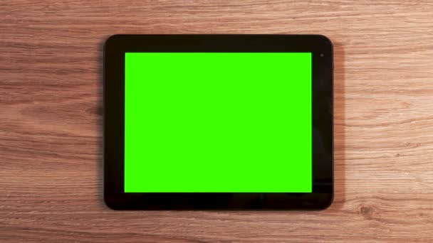 Κάτοψη στα χέρια του άνδρα με τη χρήση της λευκής οριζόντιας συσκευής tablet με πράσινη οθόνη στο ξύλινο τραπέζι. - Πλάνα, βίντεο