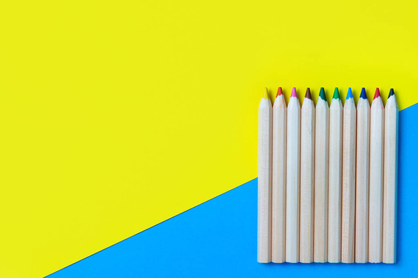Colored pencils on a blue-yellow background. Back to school. Copy space, flat layout, mockup. - Fotó, kép
