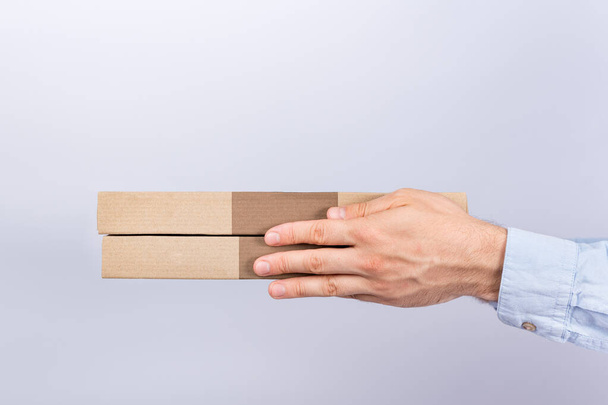 Pizza boxes in male hands. White background. Side View. Courier delivery. - 写真・画像