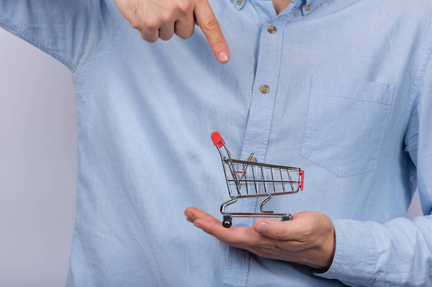 Alışveriş arabası tutan ve parmağıyla işaret eden adam. Uygun alışveriş konsepti - Fotoğraf, Görsel