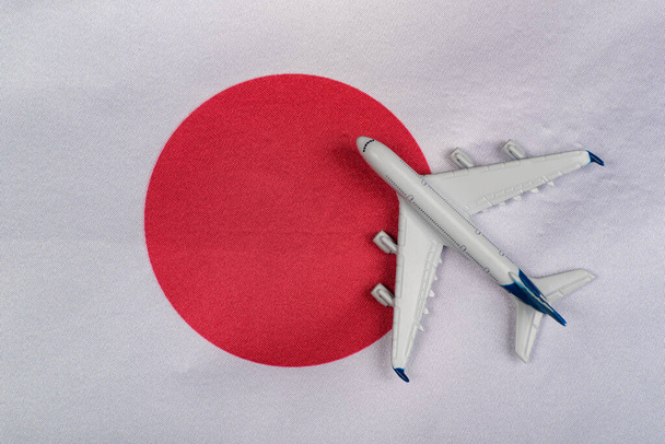Japonská vlajka a hračka letadlo zavřít. Koncept cestování letadlem do Japonska. Cesta do Japonska po karanténě - Fotografie, Obrázek