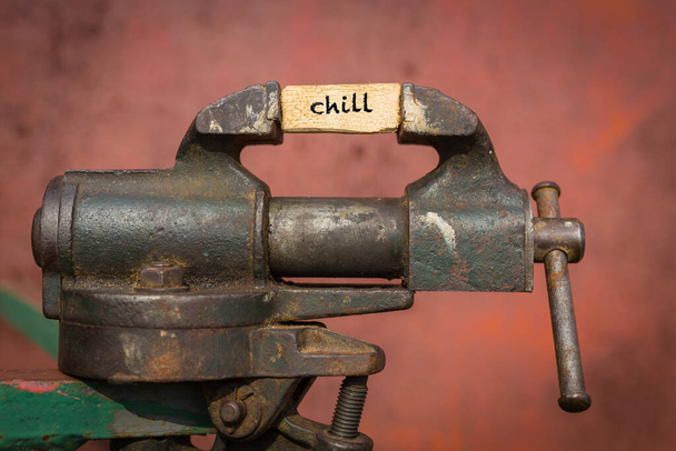 Vice grip tool squeezing a plank with the word chill - Photo, Image