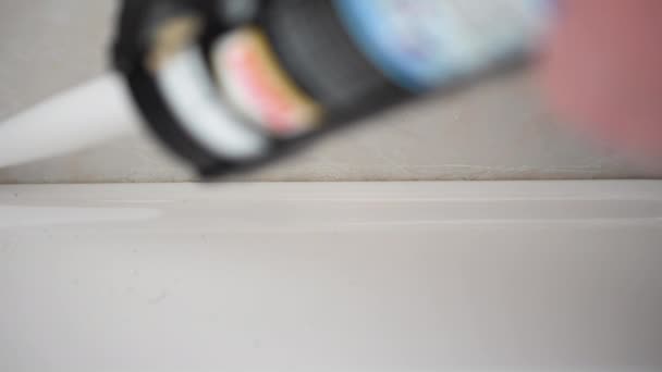 Banyodaki lavabonun mührüne silikon süren bir kanülün 4K detaylı görüntüleri. - Video, Çekim
