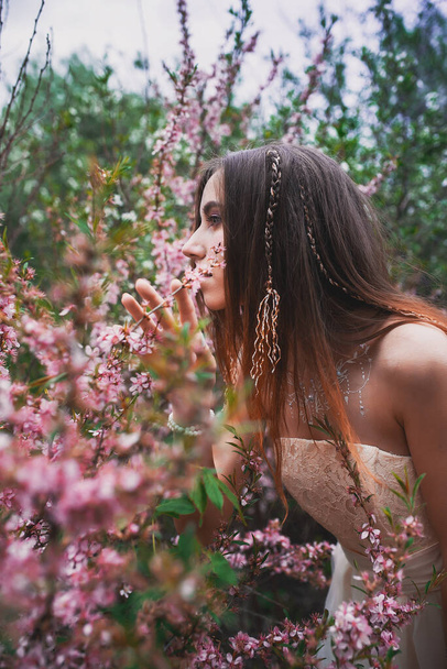 Girl in a delicate dress with mehendi on the body, in flowering almonds - Foto, Bild
