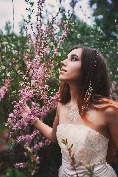 Girl in a delicate dress with mehendi on the body, in flowering almonds - Fotografie, Obrázek