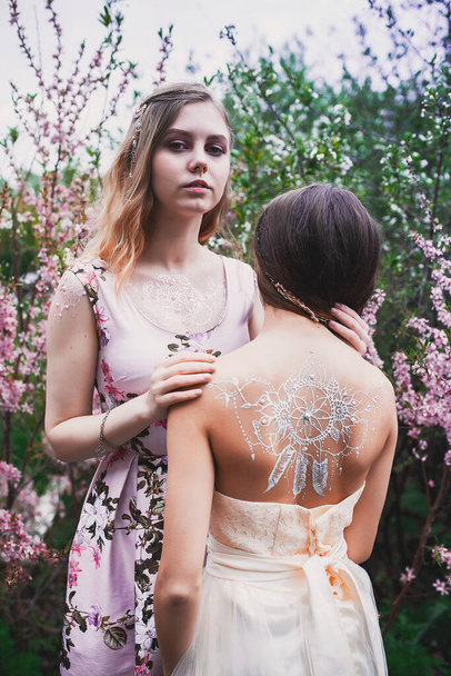 Girl in a delicate dress with mehendi on the body, in flowering almonds - Zdjęcie, obraz