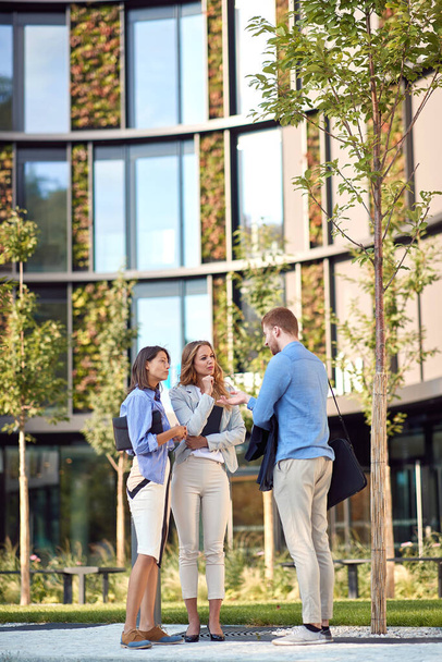 group of young business people talking in front of a building. tall, vertical image with copy cpace - Foto, imagen