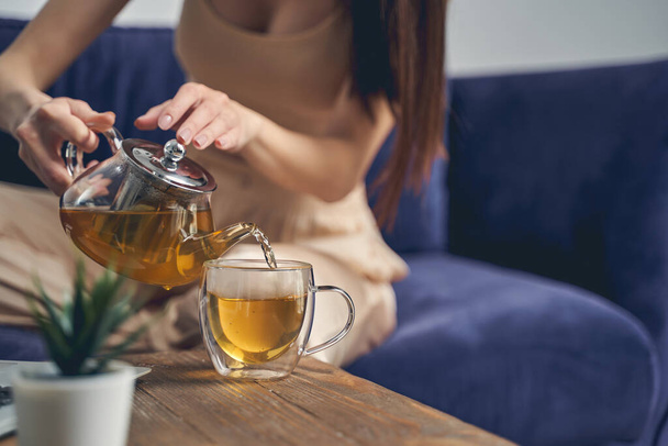 Young woman pouring herbal tea into glass cup - Foto, Imagen