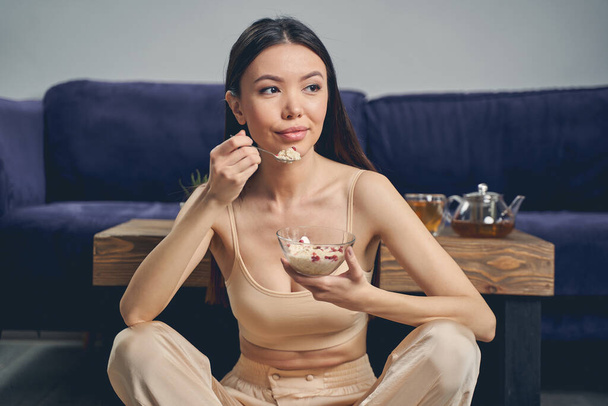 Attractive young lady eating oatmeal at home - Foto, Imagem