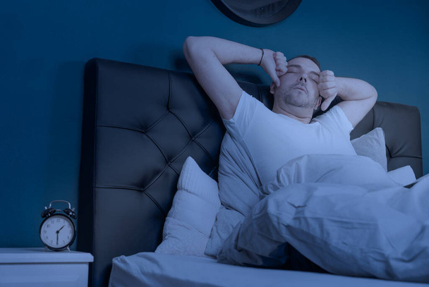 een man met slaapstoornis wordt 's nachts wakker - Foto, afbeelding