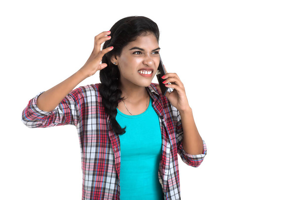 Young Indian girl using a mobile phone or smartphone isolated on a white background - Фото, изображение