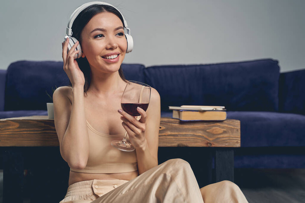 Joyful pretty lady listening to music through wireless headphones - Foto, imagen