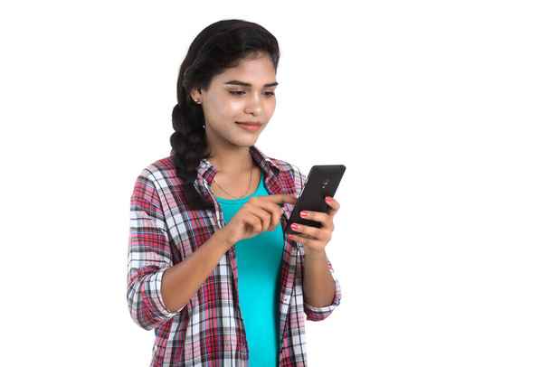 Young Indian girl using a mobile phone or smartphone isolated on a white background - Foto, Bild