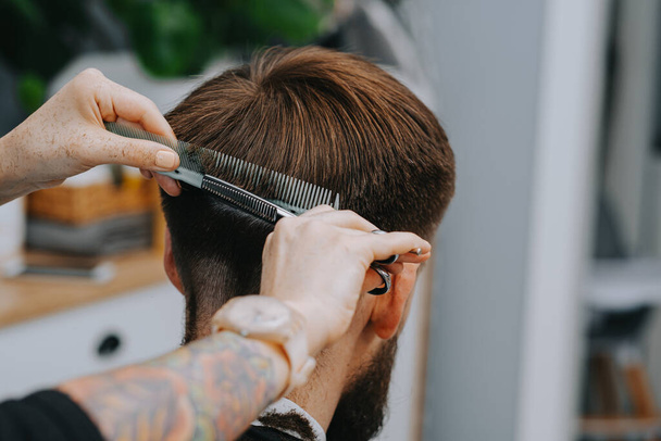 Mens haircut at home. The hairdresser cuts the hair of a man - Fotoğraf, Görsel