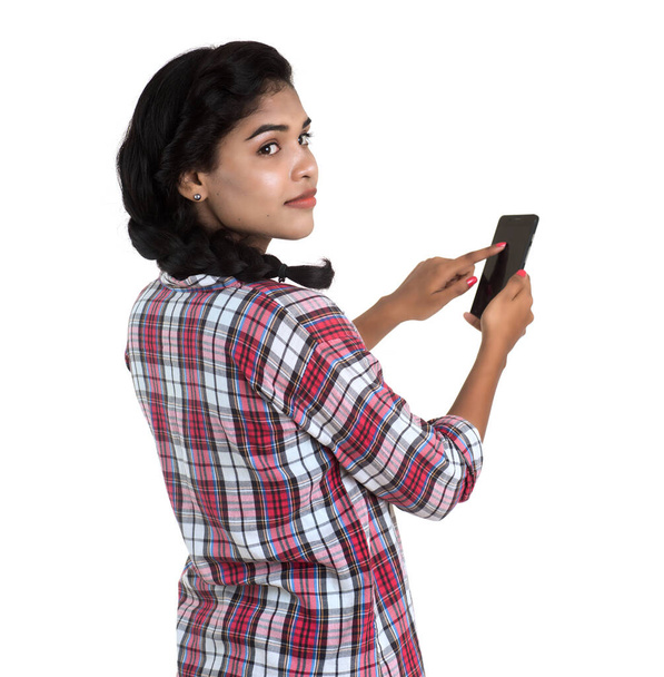 Young Indian girl using a mobile phone or smartphone isolated on a white background - Foto, Bild