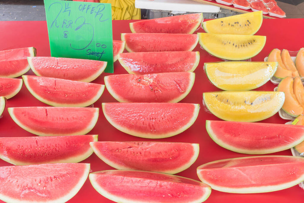 Pile of yellow and red watermelon slice cuts wrapped in cling film at street market in Singapore - Photo, Image