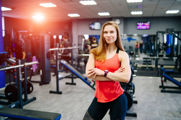 Strong sexy blonde woman with fitness muscular body posing near equipment in gym. Concept of sports healthy habits. Showing biceps. - Фото, зображення