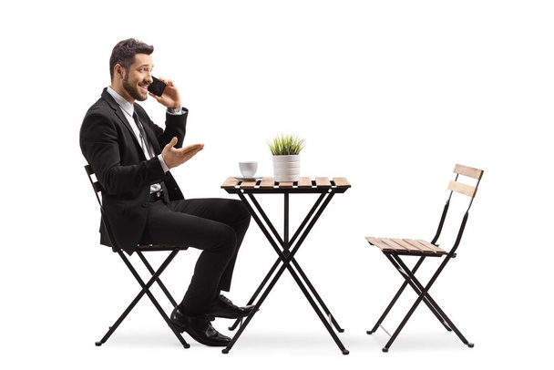 Full length profile shot of a businessman in a cafe talking on a mobile phone isolated on white background - Φωτογραφία, εικόνα
