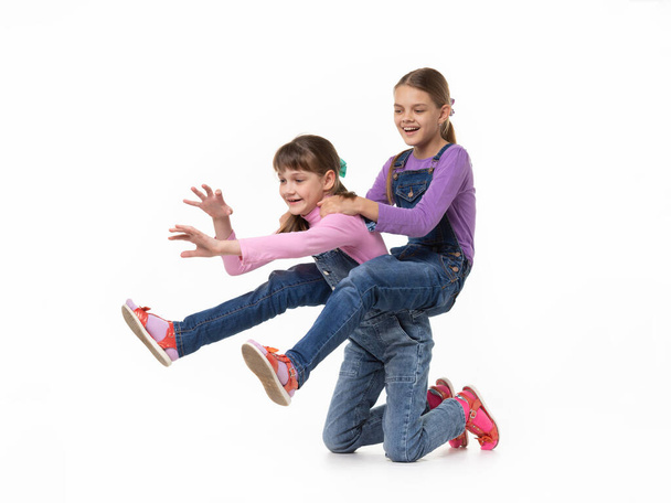 Hilarious girl rides on herself riding her sister on a white background - Photo, Image