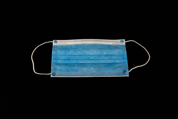 One COVID-19 protection mask isolated on black. 3 ply surgical face mask. - Foto, immagini