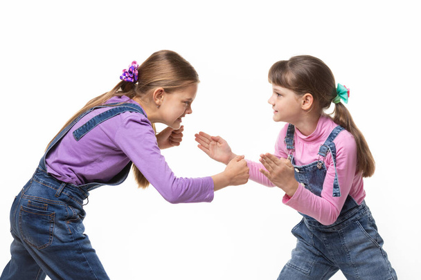 İki kız beyaz bir arka planda kavga edip kavga eder. - Fotoğraf, Görsel