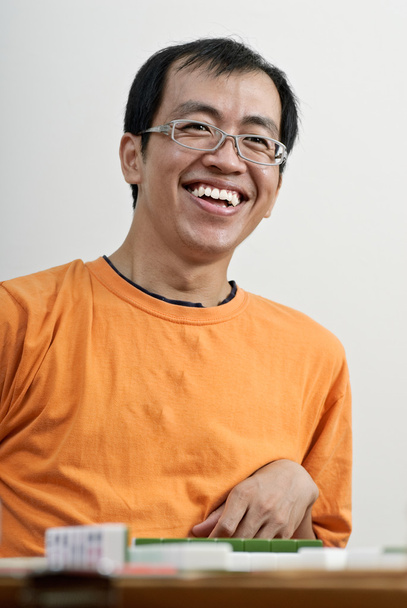 Счастливый улыбающийся азиат играет в маджонг
 - Фото, изображение