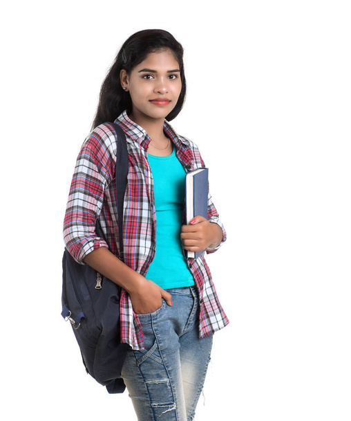 young Indian woman with backpack standing and holding notebooks, posing on a white background. - Zdjęcie, obraz