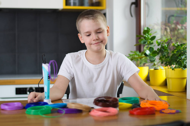 Niño usando pluma 3D. Happy boy selecciona el color del plástico ABS para usar. hobby creativo en el hogar, la tecnología, el ocio, el concepto de educación. Enfoque selectivo
. - Foto, Imagen
