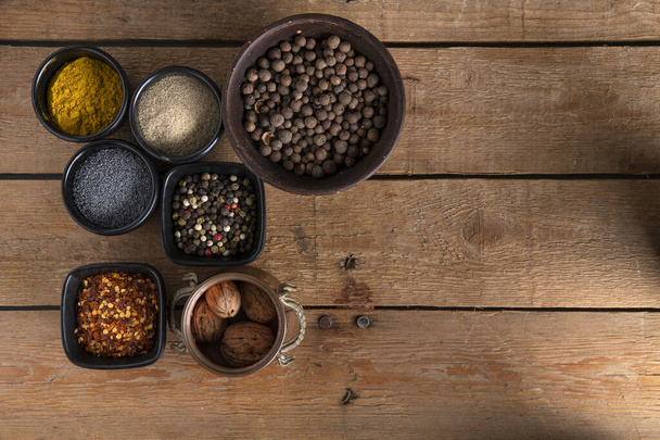 Different kind of spices in small bowls on a wooden table - Fotografie, Obrázek
