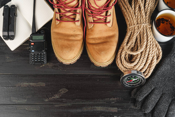 Hiking boots with equipment for hiking, cup of tea on wooden board - Foto, Bild