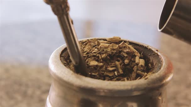 Verter agua caliente en una infusión tradicional de yerba mate en Argentina. Primer plano
.  - Metraje, vídeo