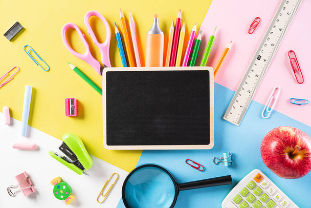 Education or back to school Concept. Top view of Colorful school supplies with books, color pencils, calculator, pen cutter clips and apple on pastel paper  background. Flat lay. - Photo, Image