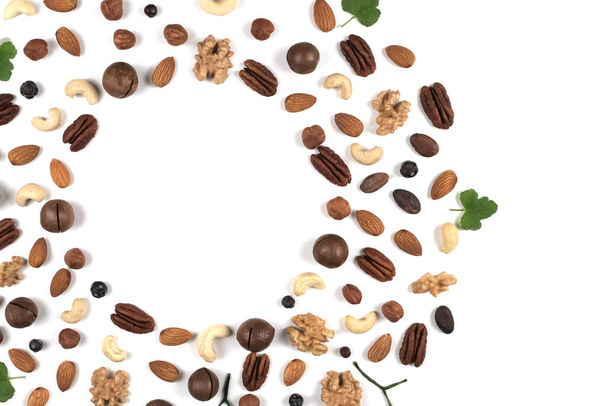 A pattern of nuts on a white background, decorated with green leaves. - Foto, imagen