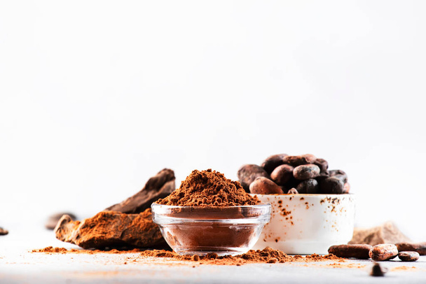 Organic cocoa powder, cocoa beans, grated cocoa lump on gray background. Copy space - Φωτογραφία, εικόνα