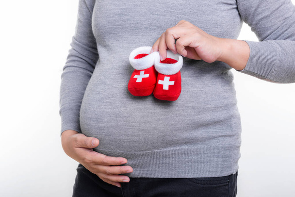 Kobieta w ciąży trzyma czerwone skarpetki dla dziecka. - Zdjęcie, obraz