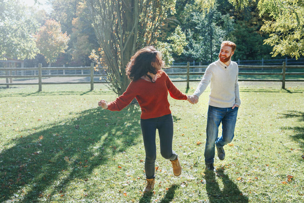 Happy couple man and woman in love walking in park outdoor. Lovely beautiful Caucasian heterosexual people dating walking on autumn fall summer day. Adult people holding hands. - Photo, Image