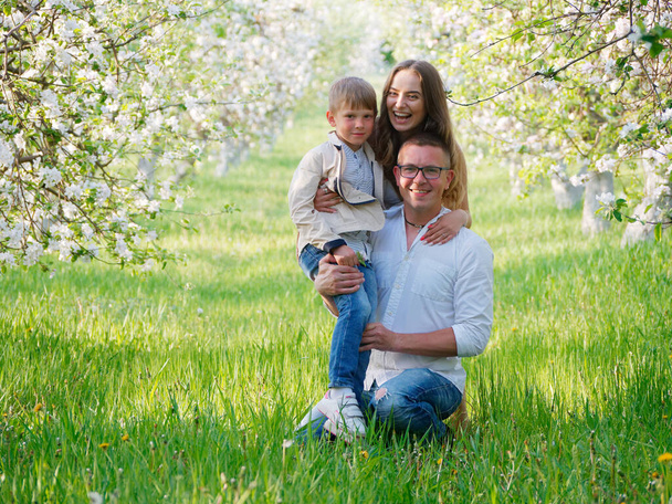 family with a child in blooming apple trees in the garden 2020 - Фото, зображення