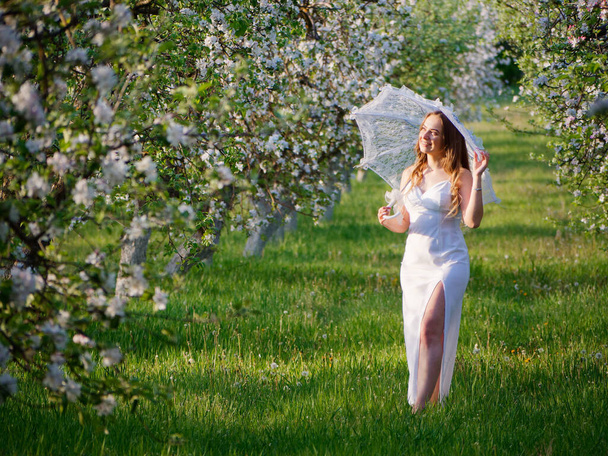 κορίτσι με λευκή ομπρέλα σε ανθισμένες μηλιές στον κήπο 2020 - Φωτογραφία, εικόνα