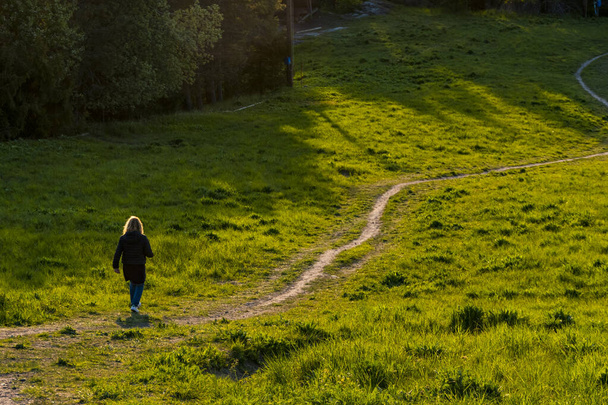 Tukholma, Ruotsi Nainen Ekeron esikaupungissa kävelee kiemurtelevaa polkua auringonlaskun aikaan
. - Valokuva, kuva