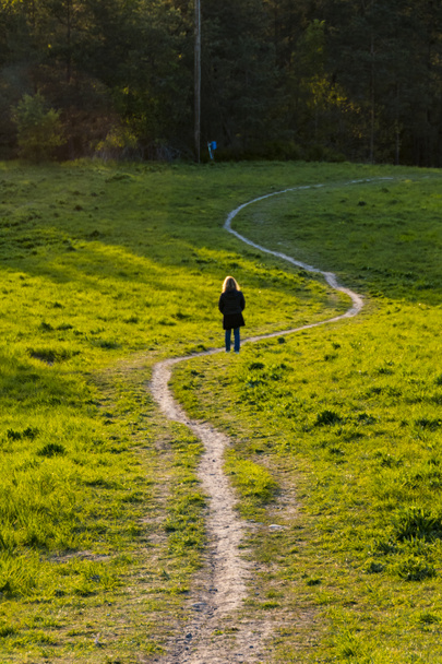 Estocolmo, Suecia Una mujer en el suburbio de Ekero camina por un sendero sinuoso al atardecer
. - Foto, imagen